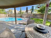Inviting backyard pool area with lush landscaping, wind chimes, and comfortable seating for outdoor relaxation at 2735 E Harwell Rd, Gilbert, AZ 85234