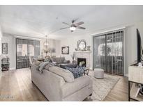 Bright living room featuring a fireplace, ceiling fan, and large windows with vertical blinds at 15252 N 100Th St # 1154, Scottsdale, AZ 85260