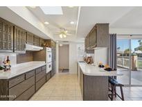 Kitchen with tile floor, a skylight and plentiful dark wood cabinets, countertop, and breakfast bar at 11113 W Cameo Dr, Sun City, AZ 85351
