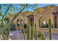 Tan stucco home featuring desert landscaping with cacti and trees, arched windows, and stone pathway at 12646 N 80Th Pl, Scottsdale, AZ 85260
