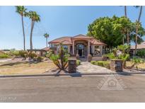 Elegant exterior elevation showcasing the home's tiled roof, lush landscaping, and inviting entrance at 3413 E Equestrian Trl, Phoenix, AZ 85044
