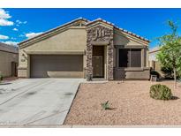 Charming single-Gathering home featuring a well-manicured front yard and a welcoming stone facade entrance and two-car garage at 30954 W Whitton Ave, Buckeye, AZ 85396