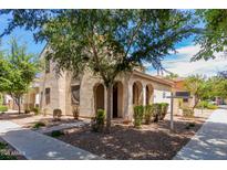 Charming stucco home with an arched entryway, mature trees, and low-maintenance landscaping at 4360 E Carla Vista Dr, Gilbert, AZ 85295