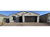 A single-story home with a two-car garage, gravel yard and a paved driveway at 15773 W Beryl Ave, Waddell, AZ 85355