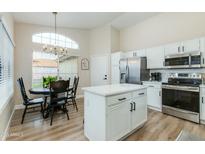 Modern kitchen featuring white cabinets, stainless steel appliances, island, breakfast nook, and large window at 21940 N 69Th Dr, Glendale, AZ 85310