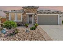 Charming stone home with a tiled roof, landscaped yard, and a gray garage door at 26733 W Melinda Ln, Buckeye, AZ 85396