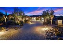 Inviting home exterior with desert landscaping, a paver driveway, and warm exterior lighting at dusk at 39254 N 104Th Pl, Scottsdale, AZ 85262