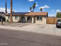 Charming single-story home with a well-maintained yard, solar panels, and mature palm trees at 5916 W Coronado Rd, Phoenix, AZ 85035