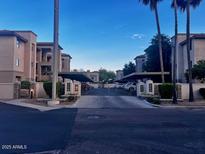 Apartment buildings with palm trees and covered parking show the front of the condo complex at 7609 E Indian Bend Rd # 1012, Scottsdale, AZ 85250