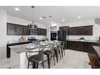Modern kitchen with granite counters, dark cabinets, and an island with bar stool seating, perfect for casual dining at 21407 W Hubbell St, Buckeye, AZ 85396