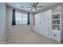 Neutral bedroom featuring built-in shelving, soft carpet, and a bright window at 2210 W Goldmine Mountain Dr, Queen Creek, AZ 85144