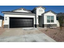 Charming single-story home featuring a black garage door, desert landscaping, and a stone-accented facade at 25207 N 183Rd Dr, Wittmann, AZ 85361