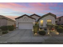 Charming home exterior featuring a two-car garage, desert landscaping and warm lighting at 26743 N 65Th Dr, Phoenix, AZ 85083