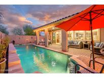 Inviting backyard pool with covered patio, lounge area, and lush landscaping, perfect for outdoor entertaining and relaxation at 15796 W Shaw Butte Dr, Surprise, AZ 85379