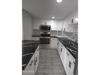 Updated kitchen featuring stainless steel appliances, white cabinets, subway tile backsplash, and gorgeous black-and-white counters at 4043 W Palomino Rd, Phoenix, AZ 85019