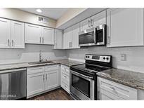 Updated kitchen featuring white cabinets, granite countertops, stainless steel appliances and subway tile backsplash at 6007 N 79Th St, Scottsdale, AZ 85250