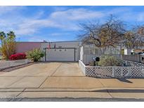 Charming home features a two-car garage, mature landscaping, and a well-maintained yard, with a white lattice fence at 6441 E Colby St, Mesa, AZ 85205