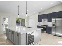 Bright kitchen features a large center island with seating, quartz countertops, wine fridge, and stainless steel appliances at 6920 W Via Montoya Dr, Glendale, AZ 85310