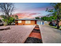 Charming brick home with a desert-landscaped front yard and a welcoming driveway at sunset at 7039 N 15Th St, Phoenix, AZ 85020