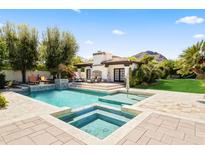 Inviting pool and spa with lush landscaping and a charming outdoor fireplace cabana, perfect for relaxation and entertaining at 5740 N Casa Blanca Dr, Paradise Valley, AZ 85253