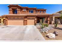 Two-story home showing desert landscaping, a covered porch, and a three-car garage at 1690 E Desert Breeze Ct, Casa Grande, AZ 85122
