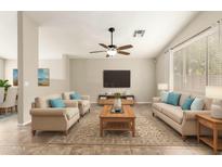 Bright living room features neutral tones, ceiling fan, and large windows for natural light at 21840 N 41St St, Phoenix, AZ 85050