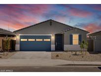 Charming single-story home featuring a blue garage door and desert landscaping at sunset at 37126 W Prado St, Maricopa, AZ 85138