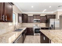 Kitchen featuring dark cabinetry, stainless steel appliances, and granite countertops at 23789 W Chipman Rd, Buckeye, AZ 85326