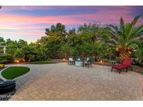 Inviting backyard patio with pavers, fire pit, chairs, and lush desert landscaping at 27949 N 130Th Ave, Peoria, AZ 85383