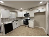 Modern kitchen featuring white cabinets, stainless steel appliances, and tile flooring at 3314 W Del Monico Ln, Phoenix, AZ 85051