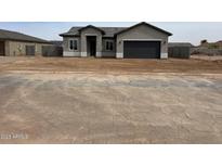 Single-story home with neutral-colored stucco, an attached two-car garage, and desert landscaping at 14861 S Capistrano Rd, Arizona City, AZ 85123