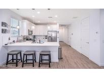 Bright kitchen with white cabinets, stainless steel appliances, and a quartz countertop island with seating at 17244 W West Wind Dr, Surprise, AZ 85387