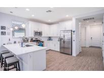 Well-lit kitchen featuring stainless steel appliances, white cabinetry, and a breakfast bar with modern stools at 17244 W West Wind Dr, Surprise, AZ 85387
