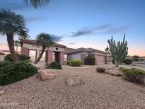 Charming single-story home with desert landscaping, rocks, and mature palm trees at 19982 N Tealstone Dr, Surprise, AZ 85374