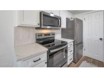 Bright kitchen features stainless steel appliances, white cabinets, and quartz countertops at 948 S Alma School Rd # 13, Mesa, AZ 85210