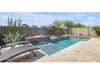 An inviting backyard pool featuring travertine tile surround and desert landscaping at 4229 W Magdalena Ln, Laveen, AZ 85339