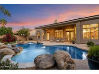 Beautiful outdoor living space with pool, rock features, and covered patio, perfect for relaxing evenings and entertaining guests at 1082 W Thompson Way, Chandler, AZ 85286