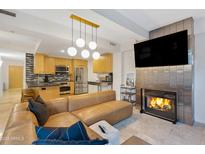 Modern living room with a fireplace, tan leather sofa, and open kitchen area at 7131 E Rancho Vista Dr # 1008, Scottsdale, AZ 85251