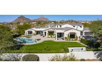 Stunning home featuring a lush lawn, pool, mountain views and a covered patio area perfect for entertaining at 10160 E Whispering Wind Dr, Scottsdale, AZ 85255