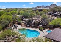 Beautiful pool and hot tub surrounded by desert landscape, boulders, and lush greenery in a gated community at 28990 N White Feather Ln # 121, Scottsdale, AZ 85262