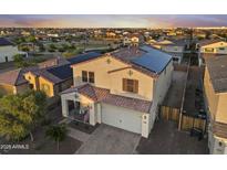 Two-story home featuring a tiled roof, solar panels, and a welcoming front porch, complemented by a well-manicured yard at 4115 S 180Th Dr, Goodyear, AZ 85338