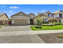 Charming single-story home features manicured lawn, brick driveway, and a two-car garage at 7407 E Portobello Ave, Mesa, AZ 85212