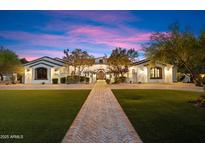 Stunning front exterior of home with manicured lawn, stone walkway, and beautiful desert landscaping at dusk at 8515 E Sutton Dr, Scottsdale, AZ 85260