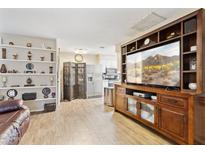 Cozy living room featuring wood floors, built in shelving, and a large entertainment center at 9021 W Elm St # 7, Phoenix, AZ 85037