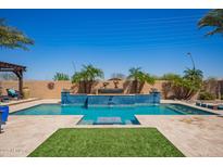Beautiful pool with waterfall feature, surrounded by palm trees and lush landscaping at 21623 S 223Rd Pl, Queen Creek, AZ 85142