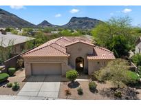 Charming desert home features a red tile roof, arched entryway, two-car garage and desert landscaping at 14037 E Coyote Rd, Scottsdale, AZ 85259
