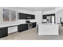 Modern kitchen with black cabinets, stainless steel appliances, and a bright island at 18525 N Larkspur Dr, Maricopa, AZ 85138