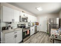 Modern kitchen features white cabinets, stainless steel appliances, and stylish gray flooring at 2221 E Lynne Ln, Phoenix, AZ 85042