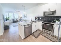 Modern kitchen with stainless steel appliances, granite countertops, and an open layout overlooking the living room at 2314 E Hidalgo Ave, Phoenix, AZ 85040