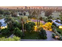 Stunning aerial view of property, showcasing lush landscaping, mature trees, and city skyline at sunset at 3006 N Manor W Dr, Phoenix, AZ 85014